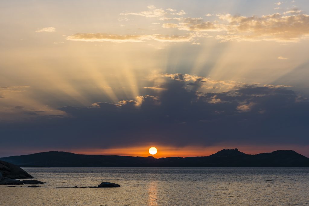 Sunset and crepuscular rays at Baya Sardinia, Sardinia, Italy