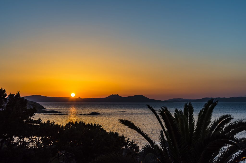 Sunset and reflections over the sea at Baya Sardinia, Sardinia, Italy