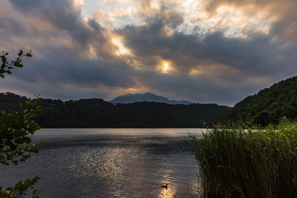 Sunset and stormy clouds over the lake at Levico Terme in the Dolomite mountains, Trentino, Italy