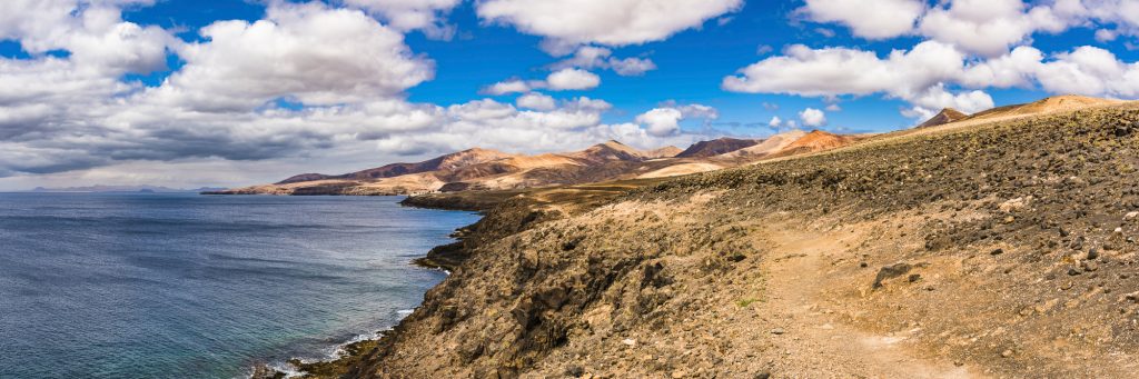 Panorama of the sea, beach, volcanic mountains and hills at Puerto Calero, Lanzarote, Spain