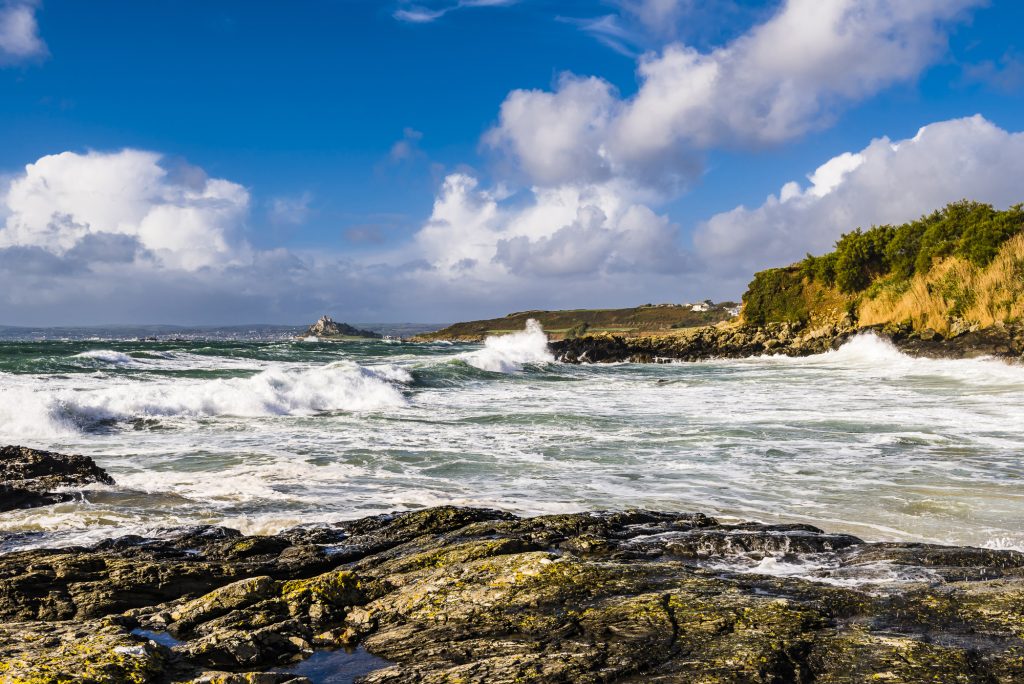 Stormy waves and surf on Trevean Cove, looking out to St Michael's Mount, near Penzance, Cornwall