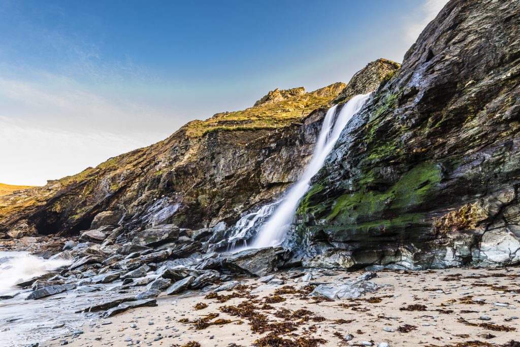 Long exposure of the waterfall crashing down on to the beach at Tintagel Haven, Tintagel, Cornwall