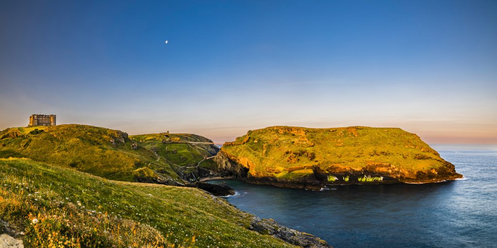 Panorama of the summer solstice sunrise light over Tintagel Island at Tintagel Haven, Tintagel, Cornwall