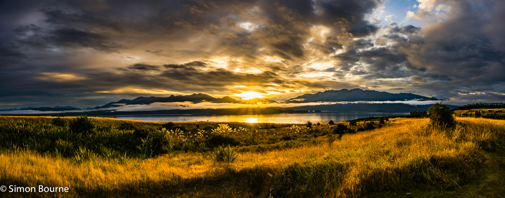 Panorama of the sunset and autumn low cloud over the mountains and waters of Lake Te Anau and the South Fiord at Fiordland National Park, Southland, South Island, New Zealand