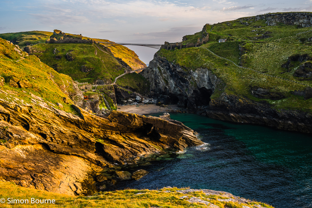 Setting sunlight at Tintagel Haven, beach, caves, waterfall, castle ruins and island on a summer's evening, Tintagel, Cornwall