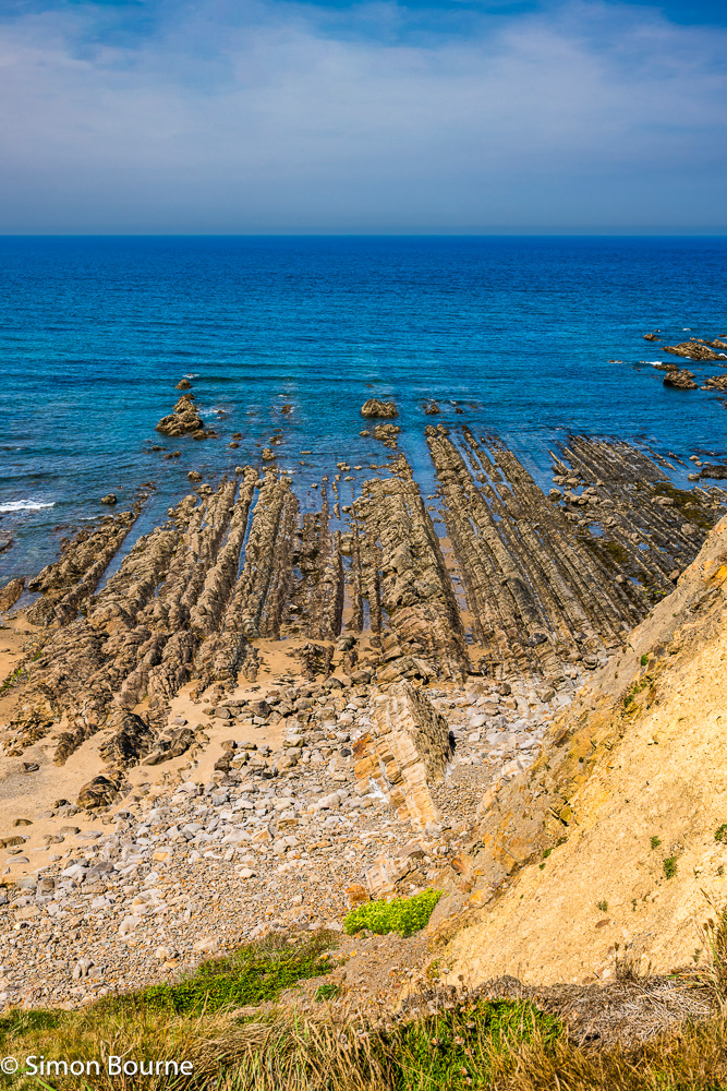 Rock formations and calm, blue Atlantic waters in the sea at Widemouth Sand beach, Cornwall